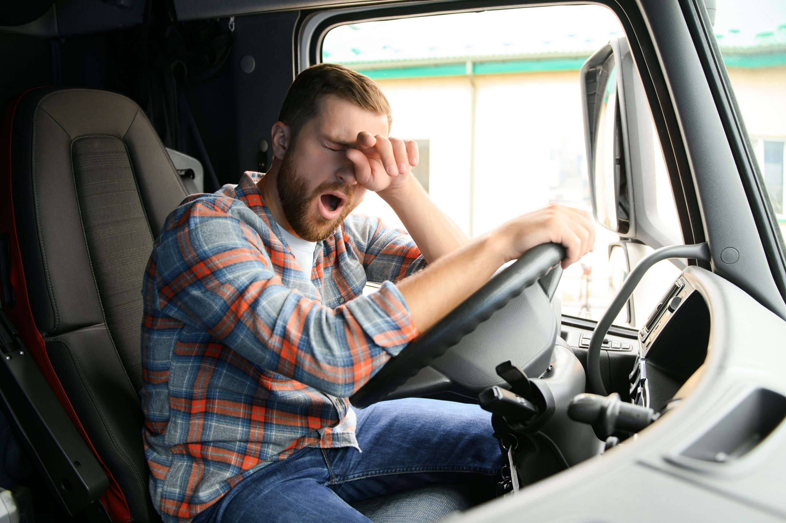 Young truck diver feeling tired and yawning during the ride