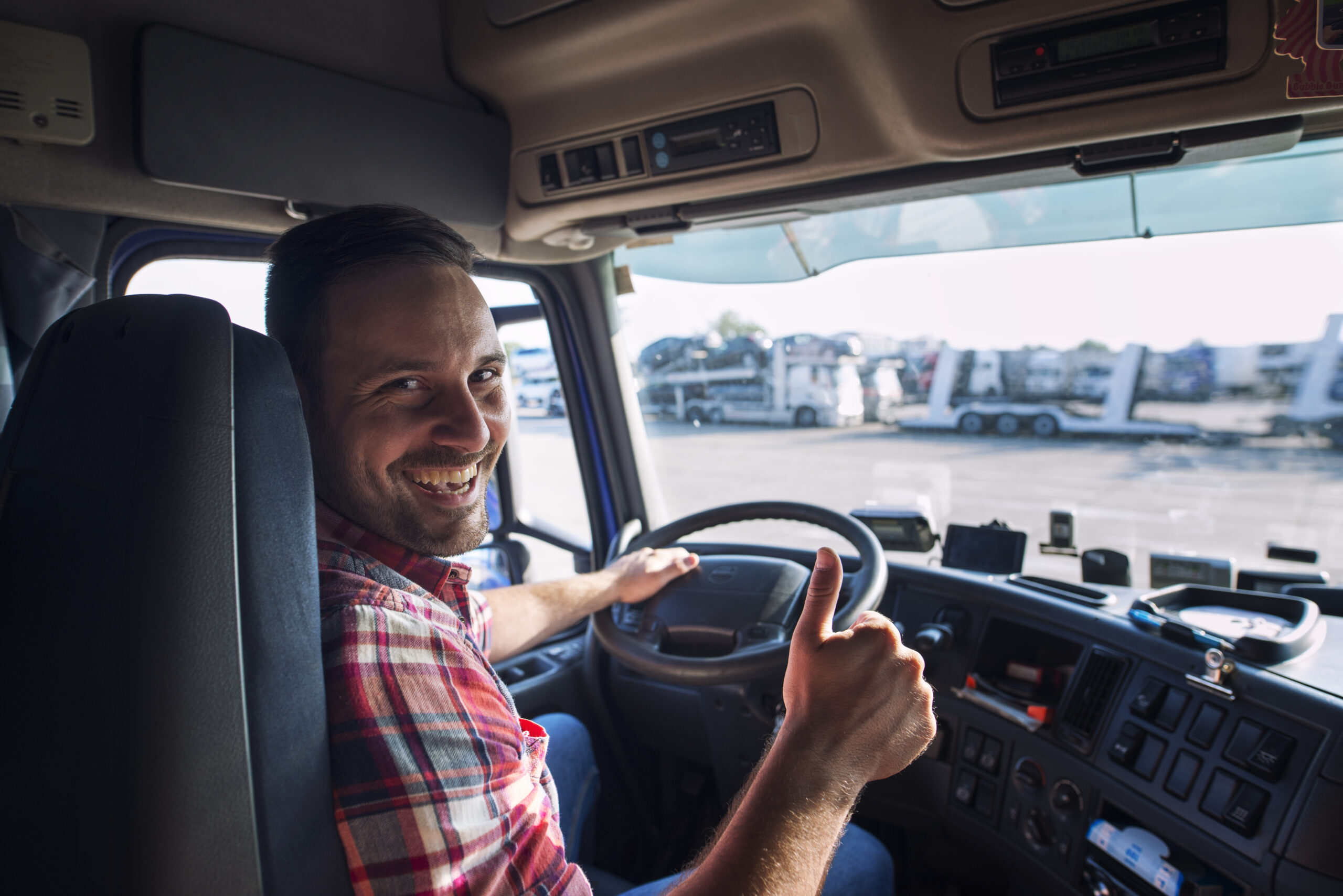 Portrait of truck driver sitting in his truck holding thumbs up.