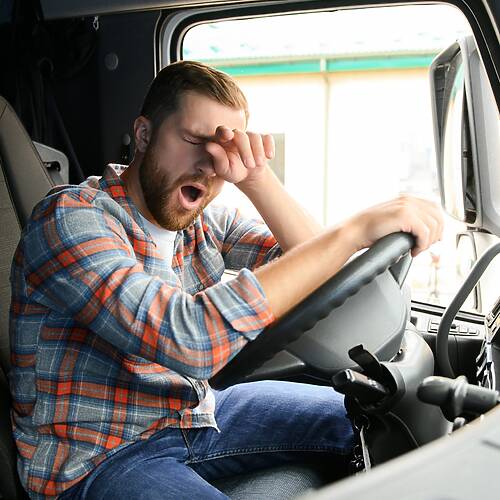 Young truck diver feeling tired and yawning during the ride