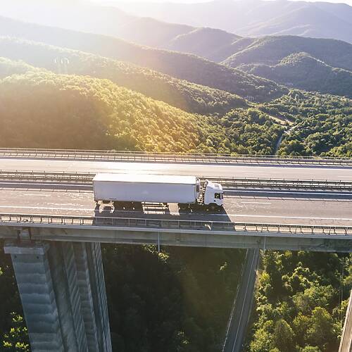 Caminhão em estrada com implemento rodoviário.